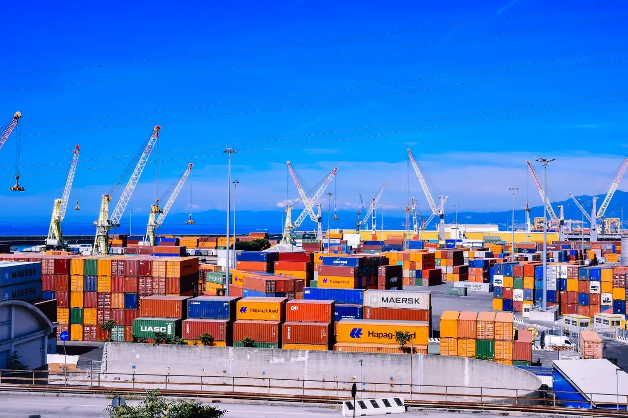 Container yard with port cranes under a blue sky