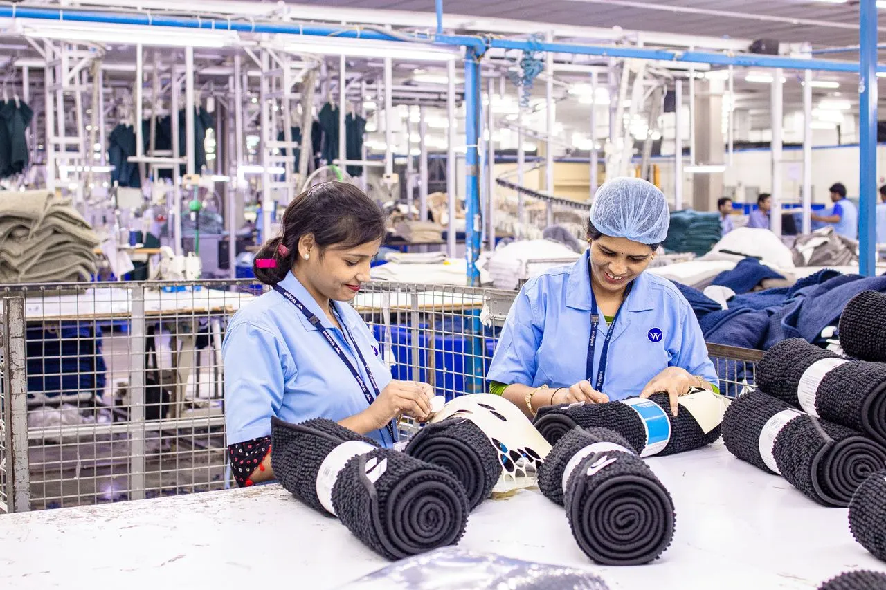 Garment factory workers stitching fabric at a production line
