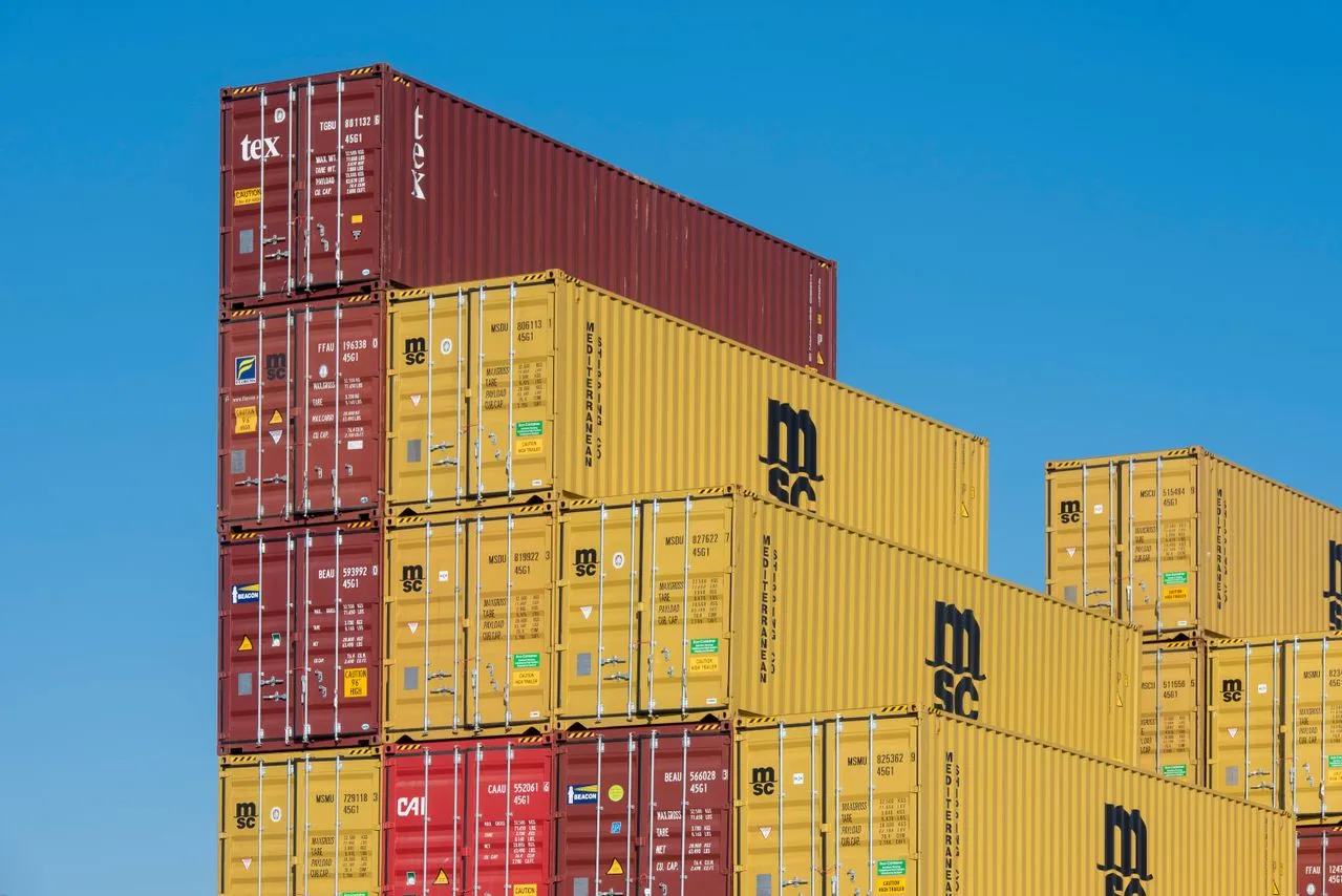Stacked shipping containers against a blue sky