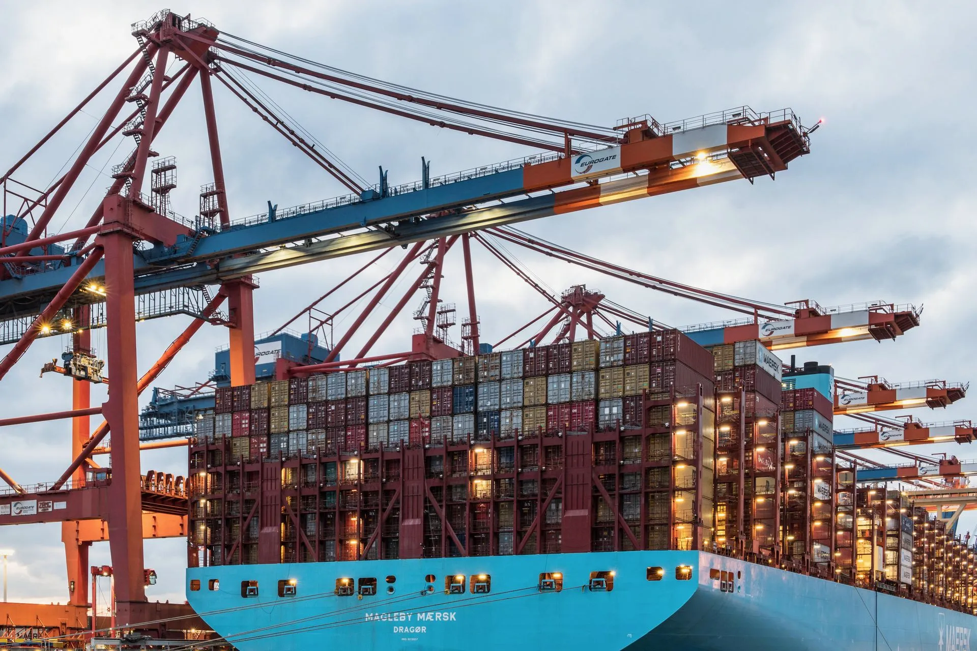 Container ship loaded by quay cranes at a port terminal